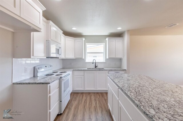 kitchen with light stone countertops, light hardwood / wood-style flooring, white cabinets, and ceiling fan