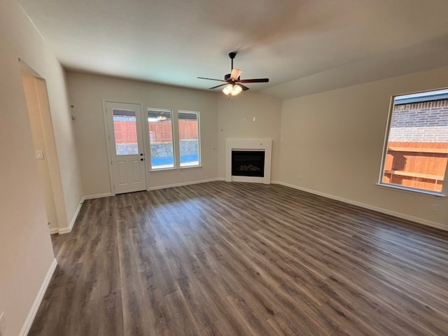 unfurnished living room with ceiling fan, dark hardwood / wood-style flooring, and a wealth of natural light