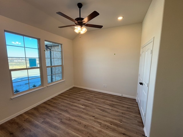 spare room featuring dark hardwood / wood-style floors, vaulted ceiling, and ceiling fan