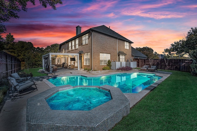 pool at dusk featuring an in ground hot tub, a yard, and a patio