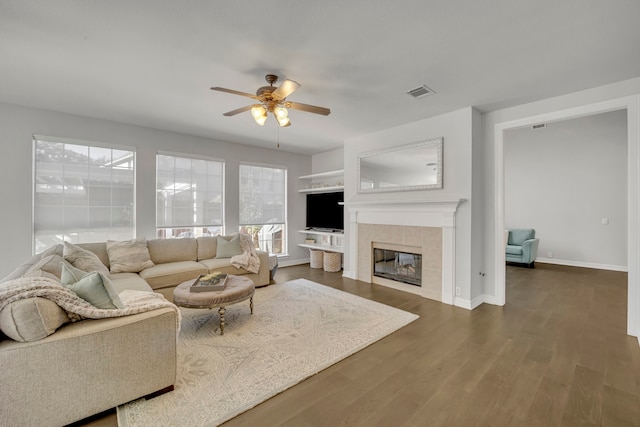 living room featuring a tile fireplace, dark hardwood / wood-style floors, and ceiling fan