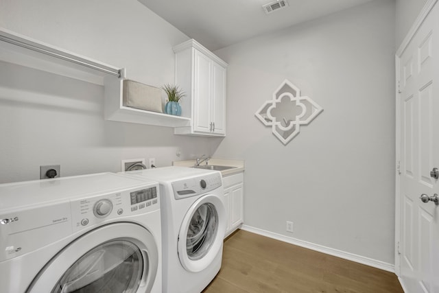 clothes washing area with cabinets, independent washer and dryer, dark hardwood / wood-style floors, and sink