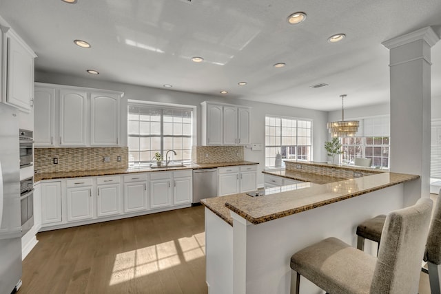 kitchen with sink, white cabinetry, hanging light fixtures, and stainless steel appliances