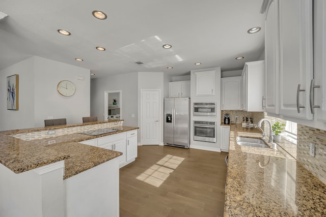 kitchen featuring stone counters, sink, decorative backsplash, white cabinets, and appliances with stainless steel finishes