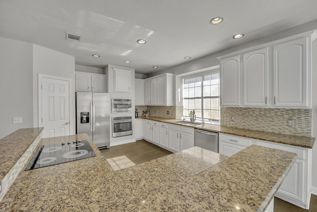 kitchen with backsplash, white cabinets, sink, light stone counters, and stainless steel appliances