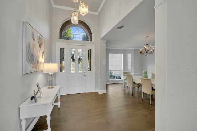 foyer with crown molding, dark wood-type flooring, and an inviting chandelier