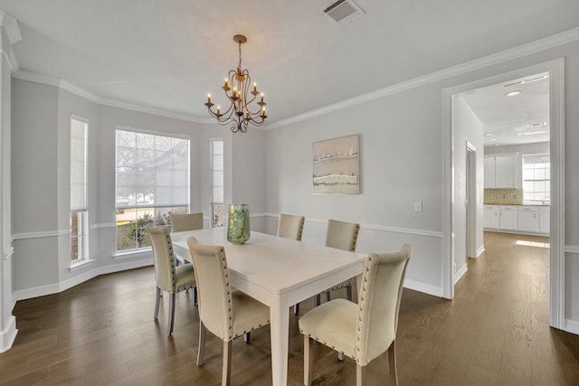 dining area featuring dark hardwood / wood-style floors, crown molding, and a notable chandelier