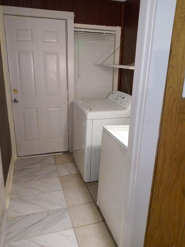 clothes washing area featuring marble finish floor, laundry area, and washing machine and clothes dryer