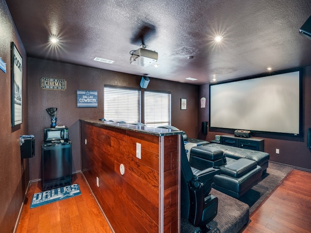 home theater featuring wood-type flooring and a textured ceiling