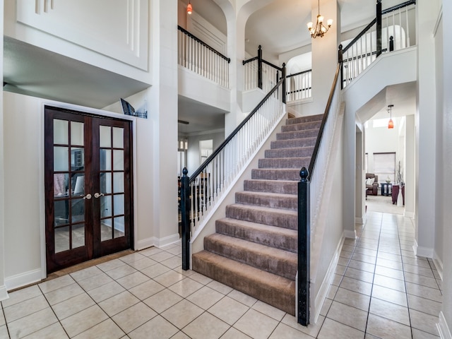 staircase featuring tile patterned floors, french doors, a high ceiling, and an inviting chandelier