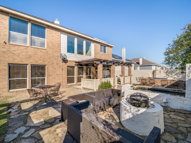 back of property with a pergola, a patio, and an outdoor living space with a fire pit