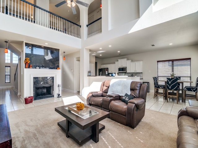 living room with ceiling fan, light tile patterned flooring, and a high ceiling