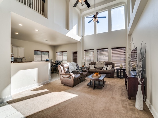 living room featuring ceiling fan, light colored carpet, and a high ceiling