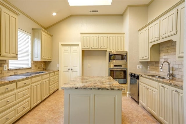 kitchen featuring cream cabinets, sink, vaulted ceiling, a kitchen island, and stainless steel appliances