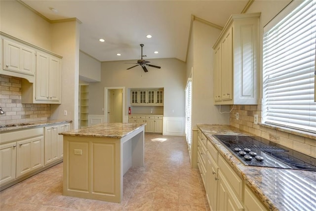 kitchen featuring vaulted ceiling, a kitchen island, black cooktop, and tasteful backsplash