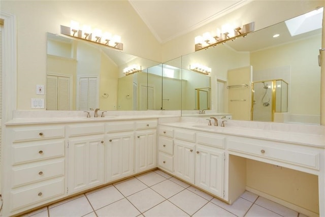 bathroom with vanity, a shower with door, lofted ceiling with skylight, tile patterned flooring, and ornamental molding