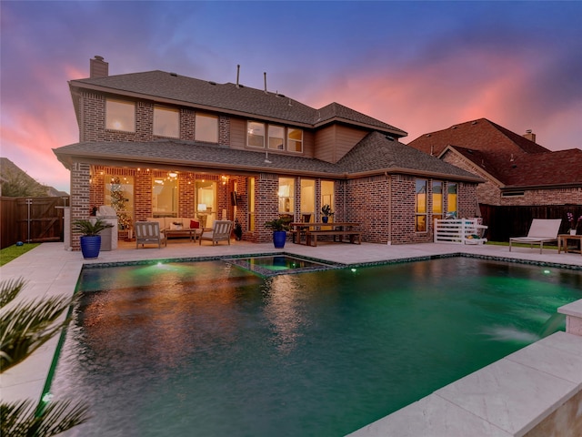 pool at dusk featuring an outdoor living space and a patio