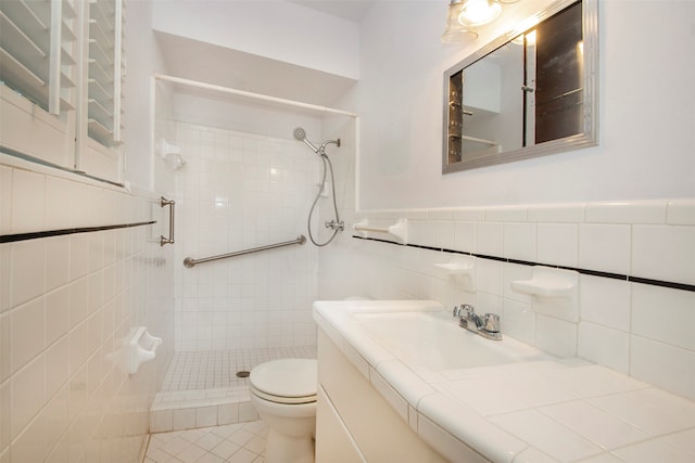 bathroom featuring vanity, toilet, tile walls, and a tile shower