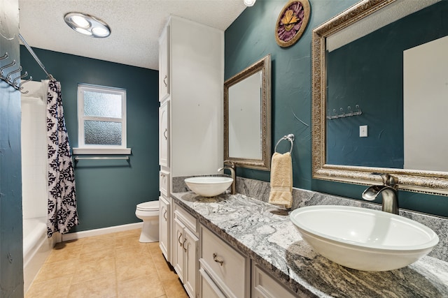 full bathroom featuring vanity, tile patterned floors, shower / bath combination with curtain, toilet, and a textured ceiling