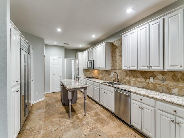 kitchen with stainless steel appliances, sink, backsplash, and light stone counters