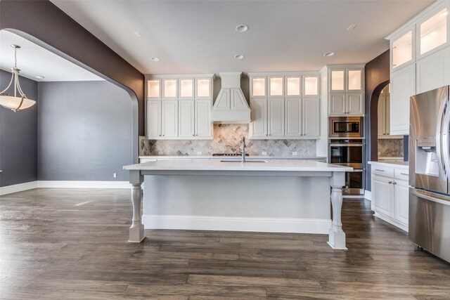 kitchen with appliances with stainless steel finishes, premium range hood, white cabinetry, and hanging light fixtures