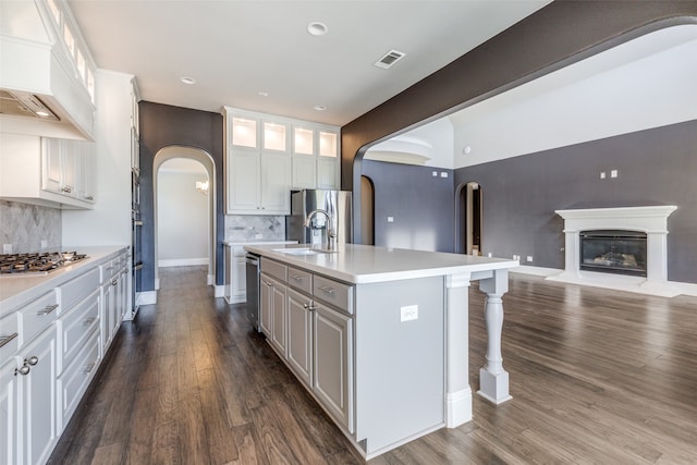 kitchen with dark hardwood / wood-style flooring, stainless steel appliances, sink, white cabinetry, and an island with sink