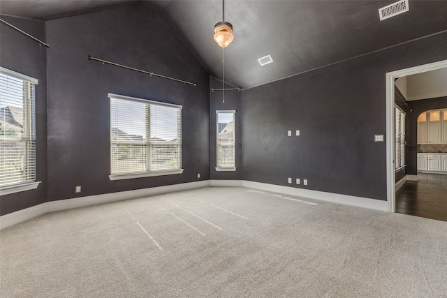 carpeted empty room featuring high vaulted ceiling