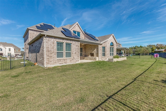 rear view of property with a yard, a patio, and solar panels