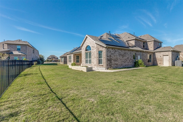 back of property featuring a yard, cooling unit, and solar panels