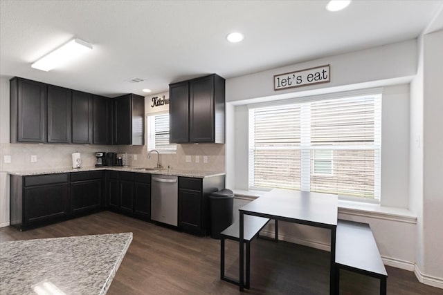 kitchen featuring dishwasher, sink, dark hardwood / wood-style floors, decorative backsplash, and light stone counters