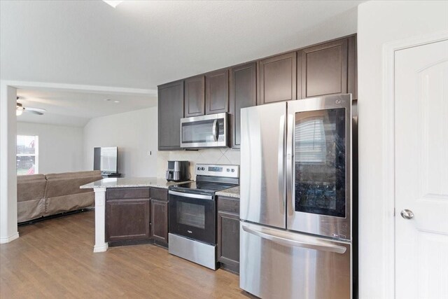 kitchen with tasteful backsplash, dark brown cabinetry, light wood-type flooring, and appliances with stainless steel finishes