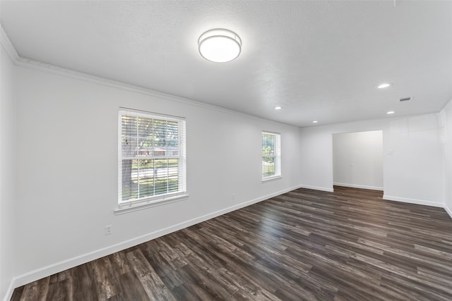 empty room featuring a textured ceiling, ornamental molding, dark wood-type flooring, and a wealth of natural light