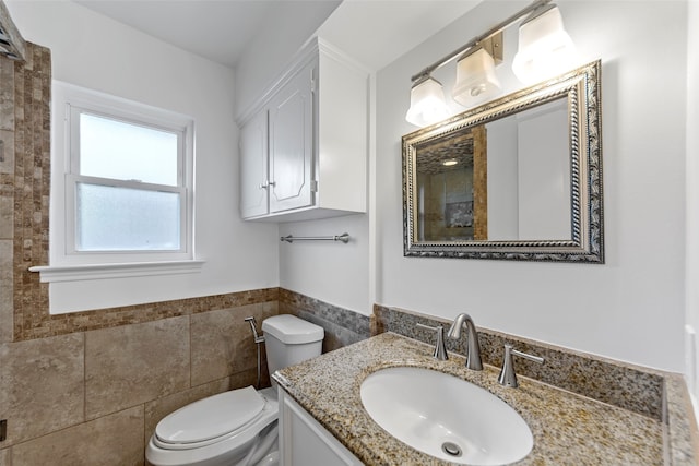 bathroom featuring vanity, toilet, and tile walls