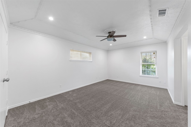 empty room featuring ceiling fan, dark carpet, vaulted ceiling, and ornamental molding