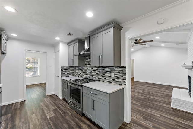 kitchen with wall chimney range hood, vaulted ceiling, dark hardwood / wood-style floors, gray cabinets, and stainless steel range oven