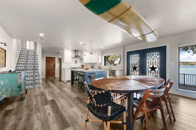 dining space with french doors, light wood-type flooring, and a water view