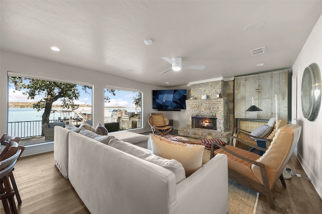 living room with ceiling fan, light hardwood / wood-style floors, a water view, and a fireplace