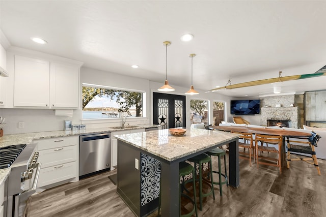 kitchen featuring white cabinets, appliances with stainless steel finishes, a kitchen island, and a fireplace