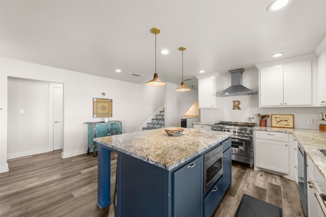 kitchen with white cabinets, wall chimney range hood, stainless steel appliances, and hardwood / wood-style flooring