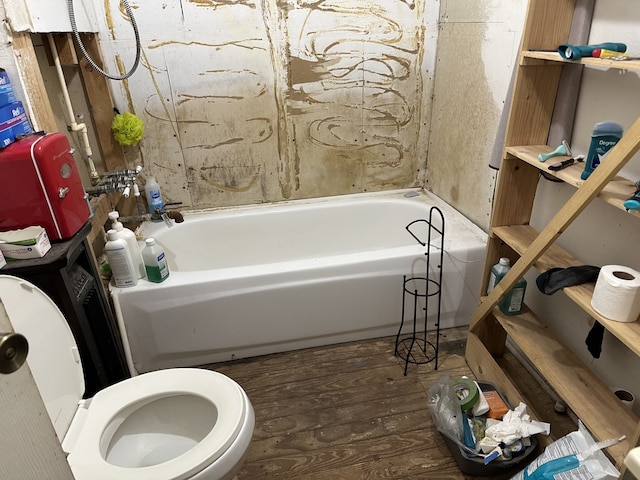 bathroom featuring a tub, hardwood / wood-style floors, and toilet