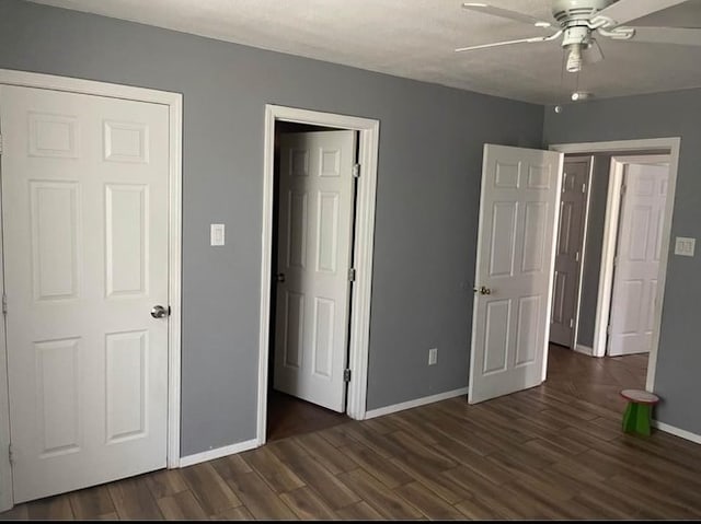 unfurnished bedroom with ceiling fan and dark wood-type flooring