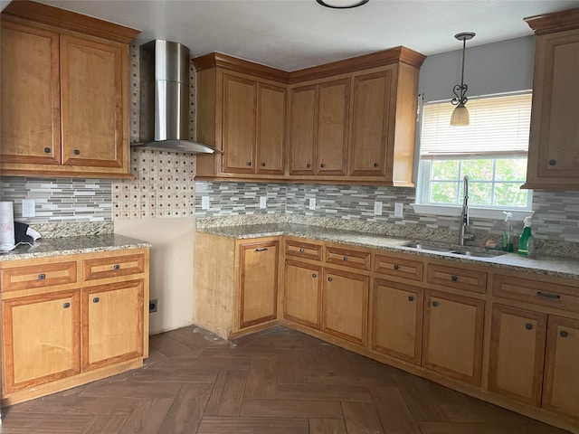 kitchen with tasteful backsplash, hanging light fixtures, wall chimney exhaust hood, and sink