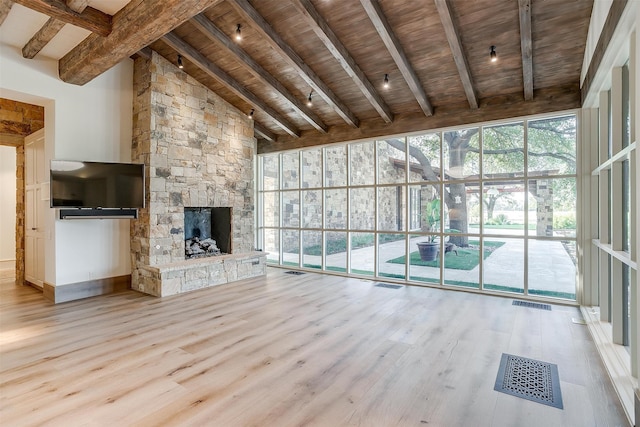 unfurnished living room featuring a stone fireplace, high vaulted ceiling, a healthy amount of sunlight, and light wood-type flooring