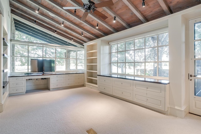 interior space featuring vaulted ceiling with beams, a healthy amount of sunlight, built in desk, and wooden ceiling