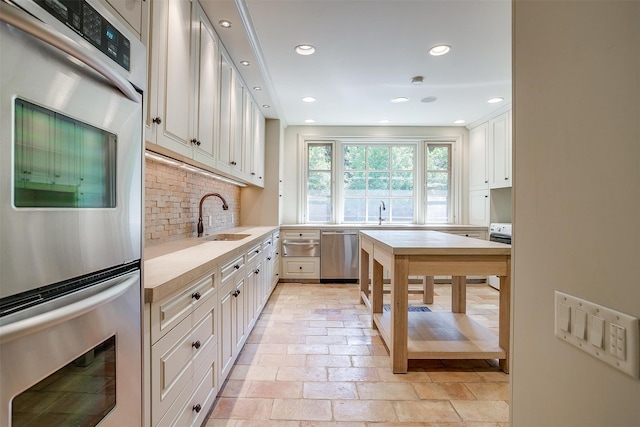 kitchen featuring backsplash, sink, white cabinets, and appliances with stainless steel finishes