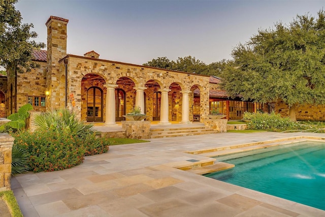 pool at dusk featuring a patio