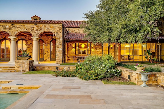 back house at dusk featuring a patio area