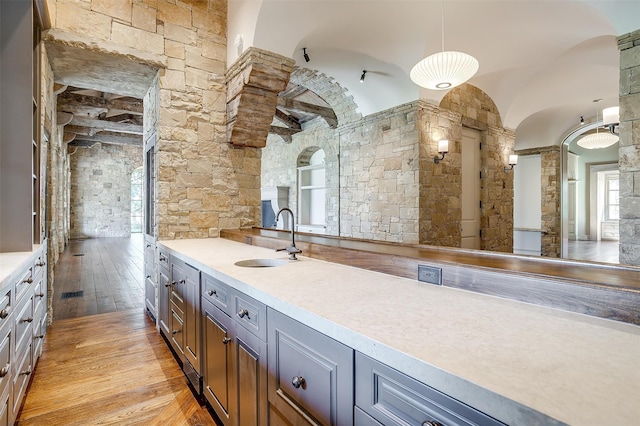 kitchen with vaulted ceiling, sink, pendant lighting, light hardwood / wood-style flooring, and gray cabinets