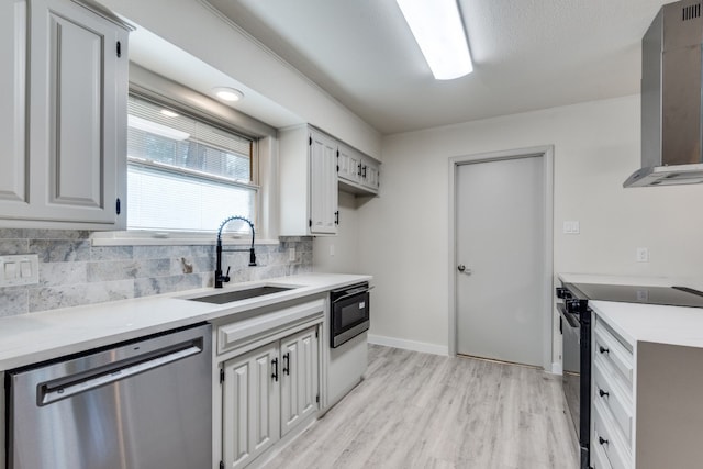 kitchen with wall chimney range hood, sink, dishwasher, light hardwood / wood-style floors, and black range with electric stovetop