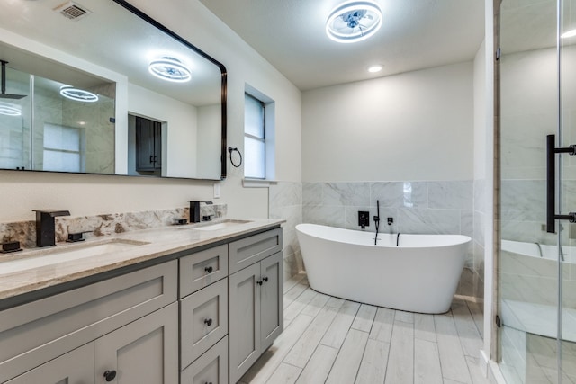 bathroom with vanity, separate shower and tub, and tile walls